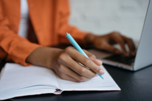 Simulated Workplace article image: depicts a student working on a computer and taking notes by hand